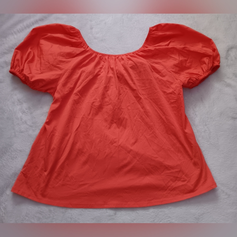 Orange/ coral colored top with puffy sleeves and tie bow in the back